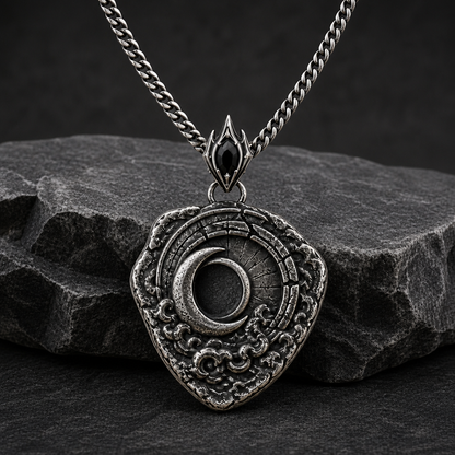 Oxidized 925 sterling silver shield pendant with raised crescent moon, dark circular center, textured relief details, pointed bail, and curb chain on beige fabric.