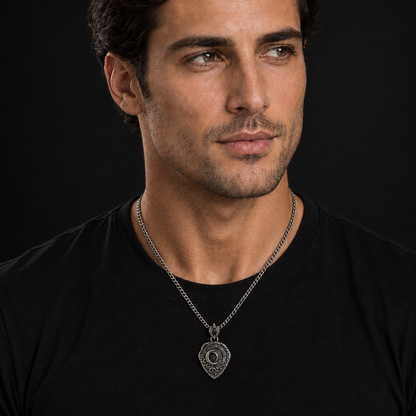 Oxidized 925 sterling silver shield pendant with raised crescent moon, dark circular center, textured relief details, pointed bail, and curb chain on beige fabric.