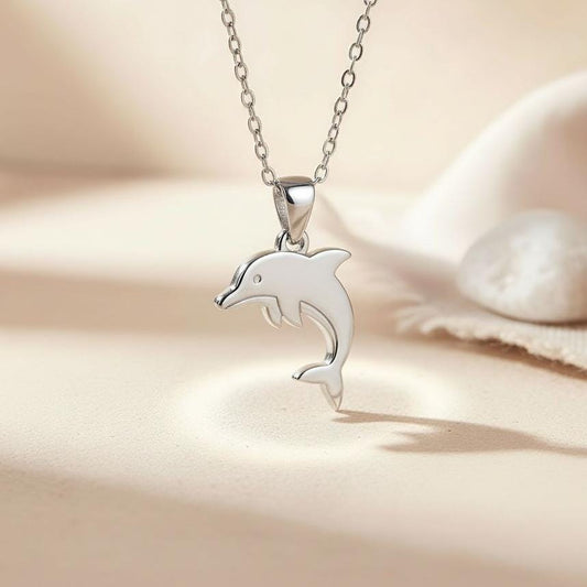 Silver leaping dolphin pendant necklace on a light fabric surface